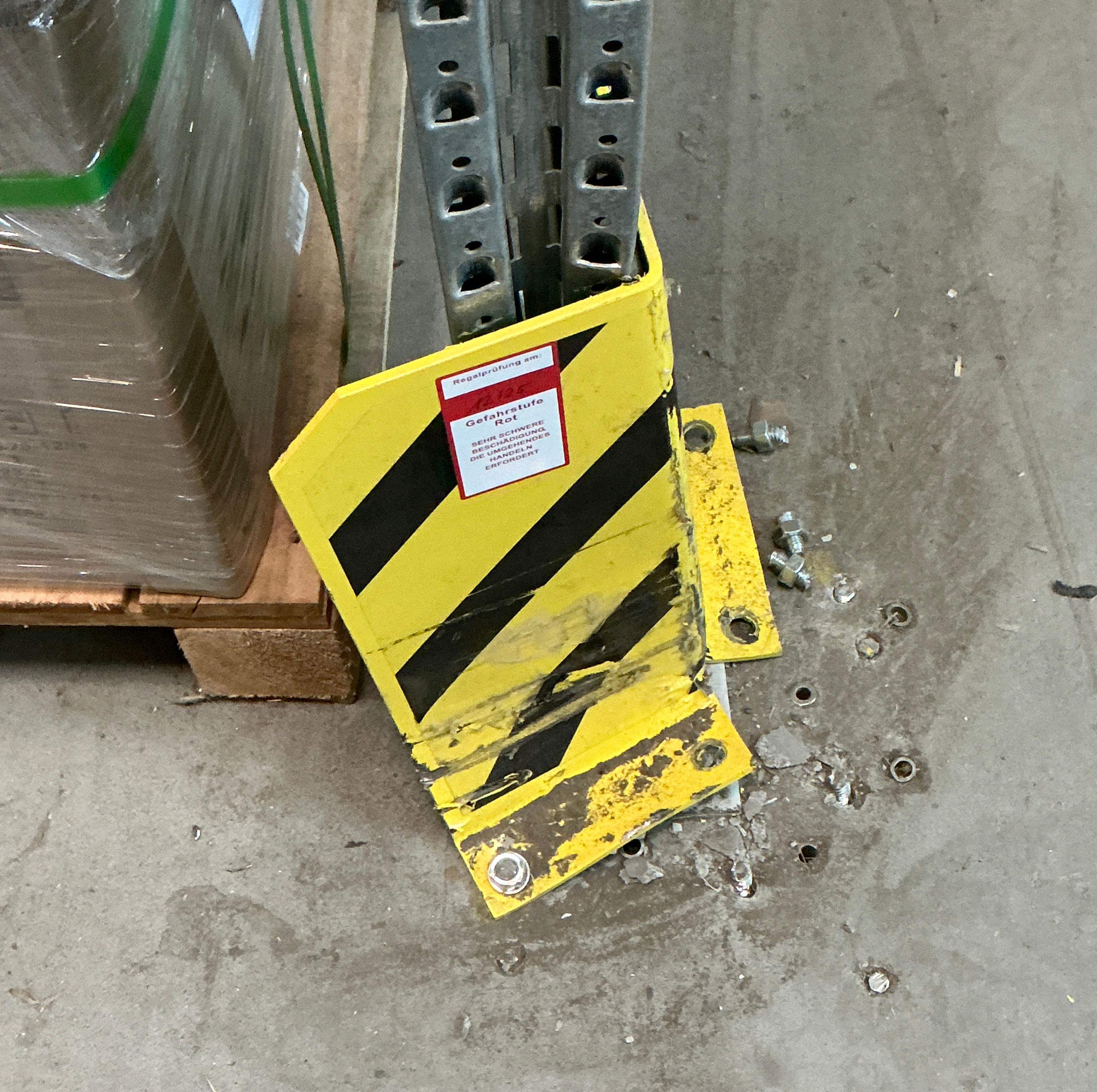 Beschädigter gelb schwarzer Anfahrschutz an einem Lagerregal